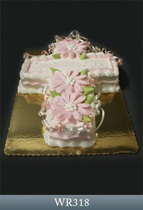 A cross cake with pink flowers on top of it.