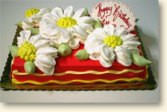 A red and yellow cake with white flowers on top.