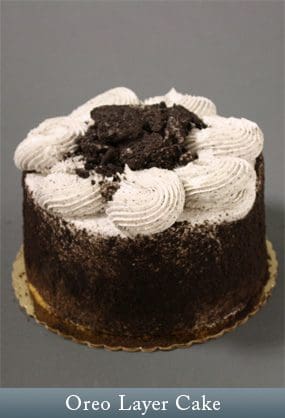 A cake with white frosting and cookies on top.