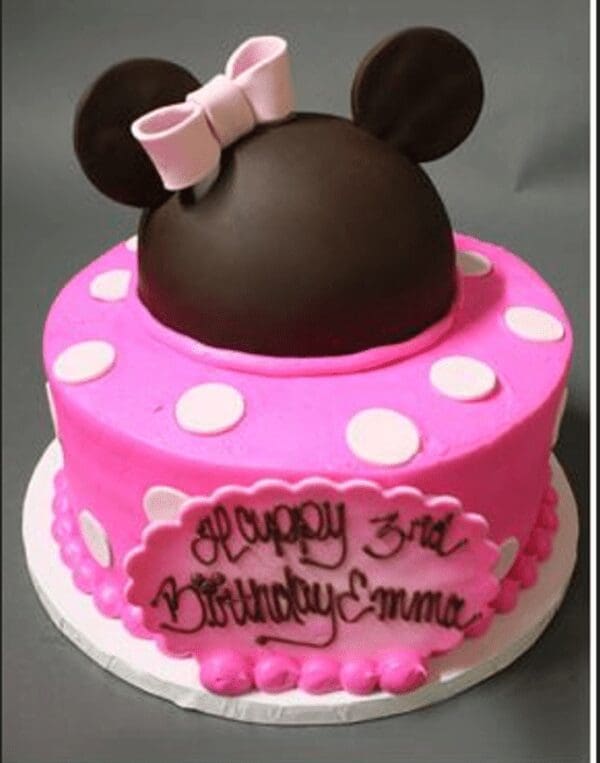 A pink and white polka dot cake with minnie mouse ears on top.