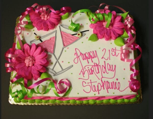 A birthday cake with pink flowers and green leaves.