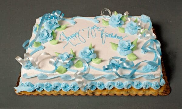 A birthday cake with blue flowers and ribbons.