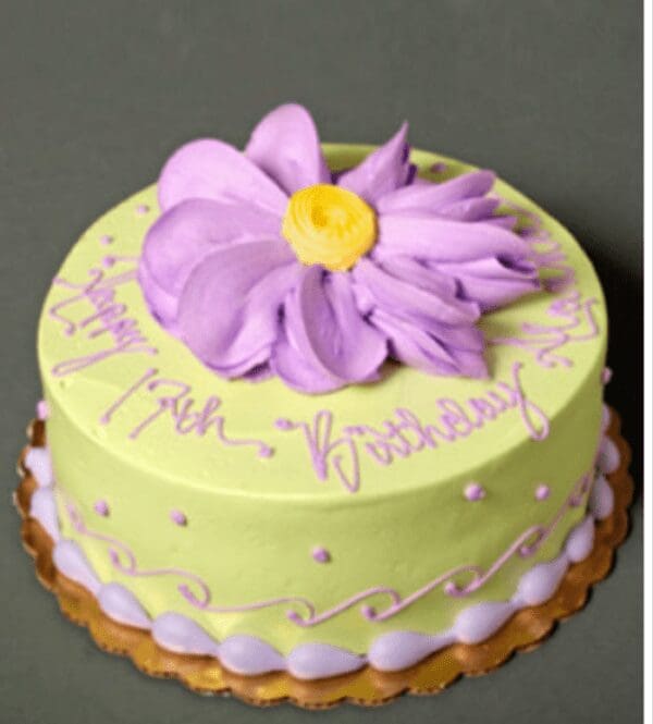 A birthday cake with a large purple flower on top.