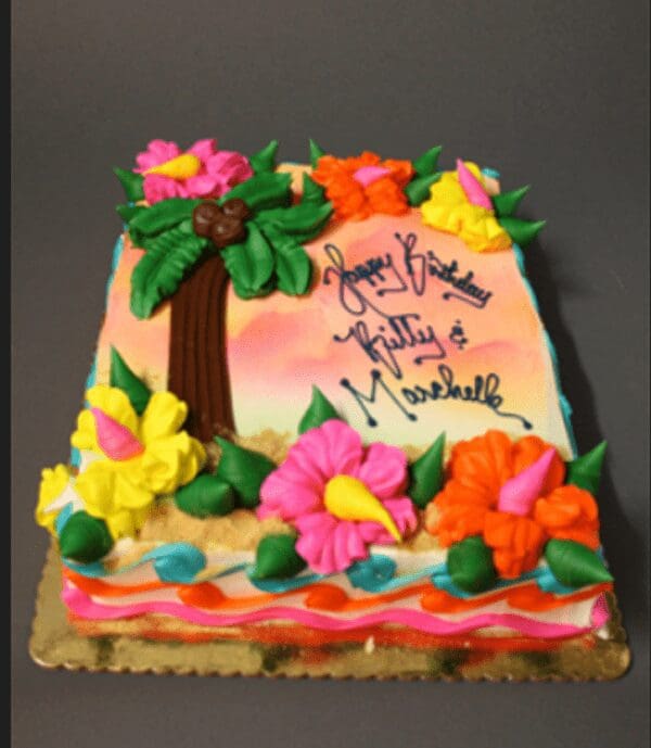 A cake with flowers and palm trees on it.