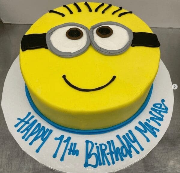 A yellow and blue cake with a minion face on it