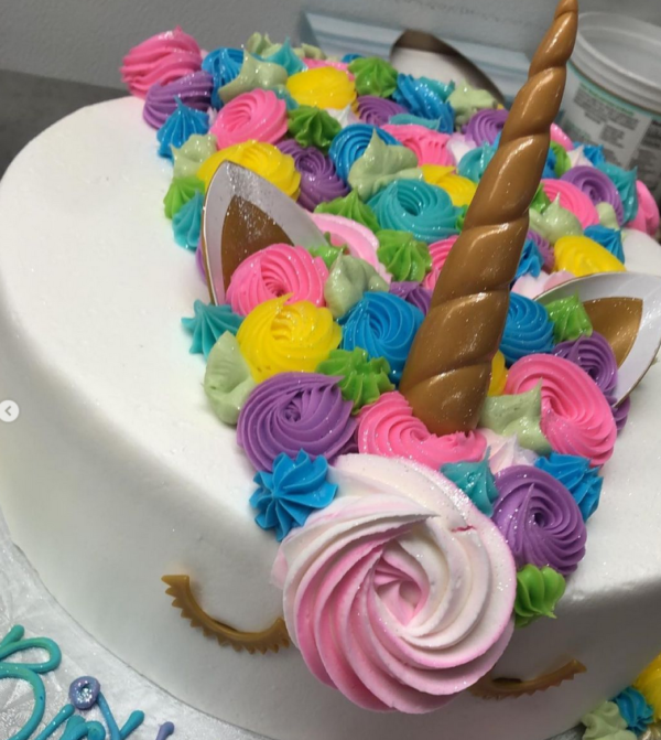 A cake with unicorn horn and ears on top of it.