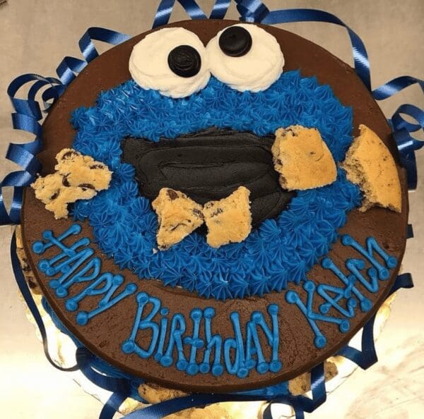 A cookie monster birthday cake with blue frosting and cookies.