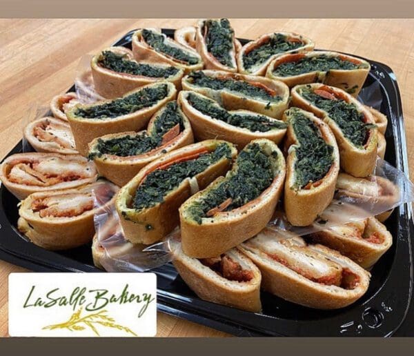 A tray of sandwiches with spinach on top.