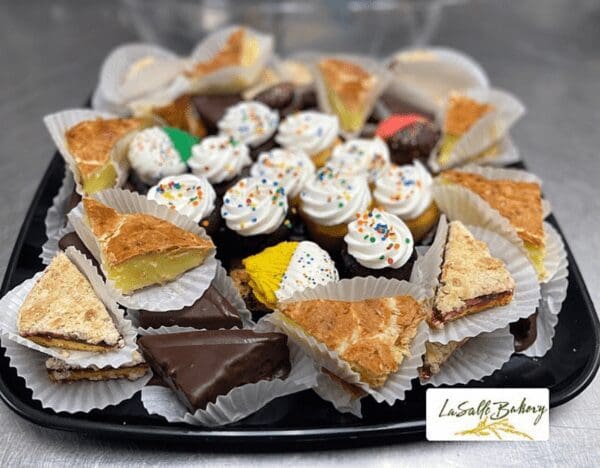 A plate of cupcakes and other pastries on top of a table.