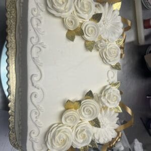 Rectangular cake with white roses and leaves.